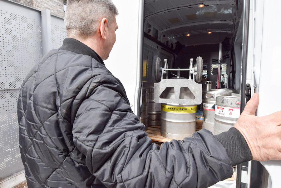 Man closing door on shipping truck full of kegs